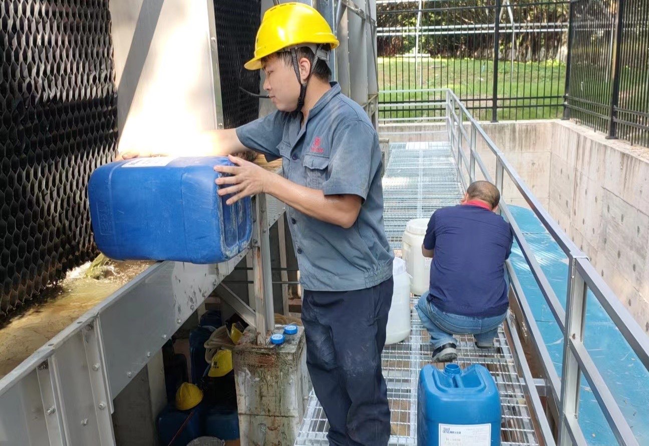Teknisi menuang treatment chemical ke basin cooling tower
